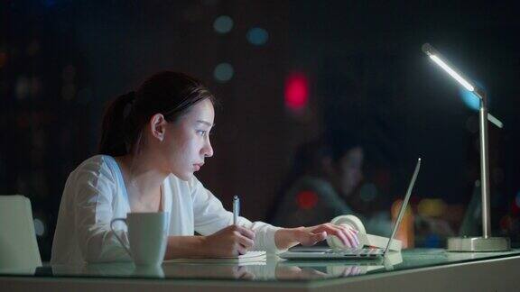 亚洲年轻的女商人在晚上使用笔记本电脑在线学习和工作