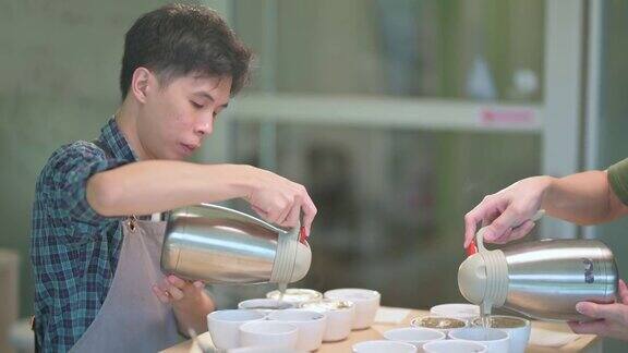 2.专业亚洲华人咖啡师将热水倒入陶瓷咖啡杯中为咖啡的拔火罐准备咖啡品质测试