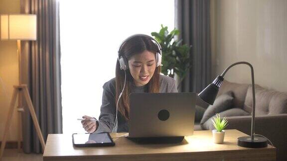 亚洲商务女性穿着休闲服装用笔记本电脑在家里的客厅里与客户支持进行视频电话会议