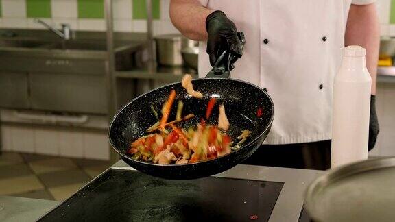 厨师在厨房的煎锅上搅拌肉和蔬菜的特写