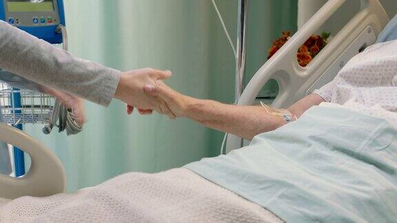 医院护士在病床上牵着老妇人的手安慰住院康复的老年病人医务人员在床边给予鼓励和保健支持
