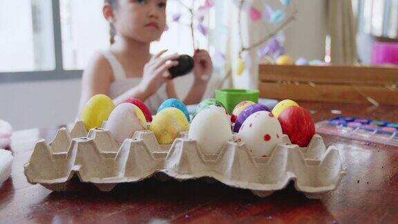 一个亚洲女孩和她的家人在给鸡蛋着色孩子和家人准备复活节画和装饰蛋