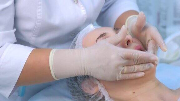 美容师正在用乳霜给女士脸上做面部和颈部按摩