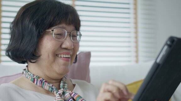 坦率的亚洲退休老太太使用平板电脑在线转账或金融支付和阅读文字微笑或笑与快乐和积极资深亚洲与数字技术概念