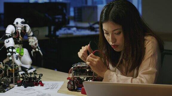 年轻的亚洲女性电子开发工程师与机器人一起工作在车间测量机器人原型电路中的信号有技术或创新观念的人