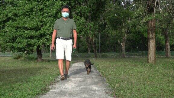 一名戴口罩的男子在公园遛狗流感流行期间与宠物狗进行户外运动
