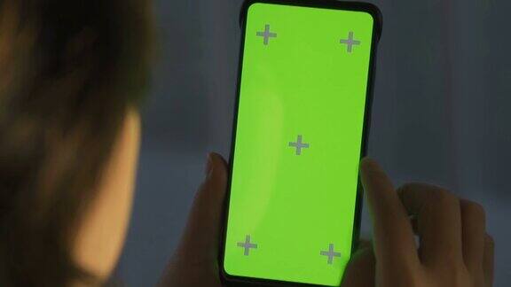 女人在家里使用智能手机的绿色屏幕