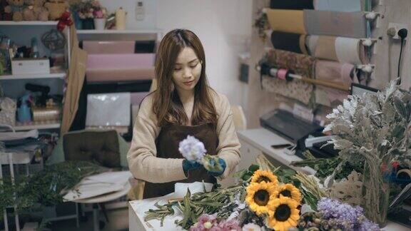 亚洲华人女花商小企业主在花店切割和安排花束日常经营小生意