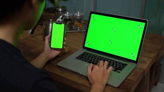 用绿色屏幕的笔记本电脑和手机的人