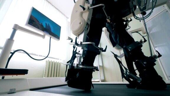 在行走练习中男人的腿被绑在训练机器上的特写康复用电子医疗机器人