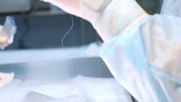 外科医生用手术针和线打开无菌包装外科医生用针架取出针头并将其从包装中抽出