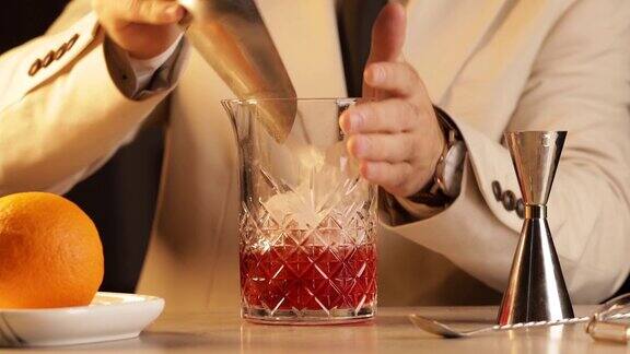 调酒师将冰块倒入调酒杯中调制一杯内格罗尼鸡尾酒