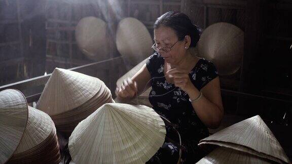 在越南Cantho省的ApThoiPhuoc村的老越南工匠制作传统越南帽子的4k镜头低光场景传统艺术家