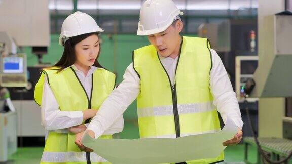 男性和女性工业工程师站在重工业制造工厂看项目蓝图技术工业科学创新工业4.0妇女在STEM自动化-大规模工业概念