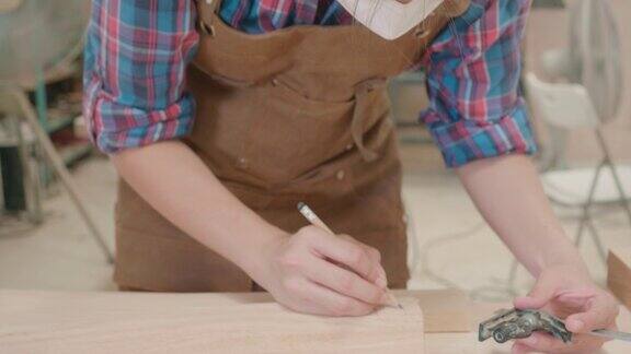 女木匠使用铅笔和尺子在木板上工作