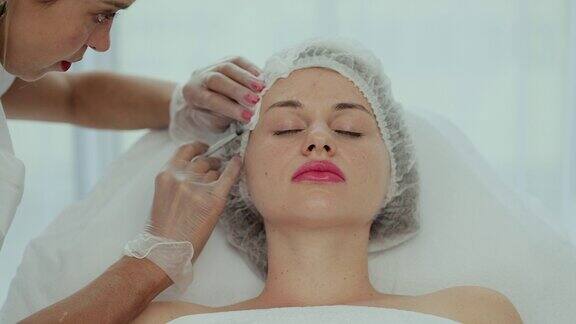 美容师医生给一个年轻漂亮的女人脸上的皮肤注射俯视图特写富血小板等离子体面部注射程序