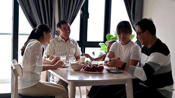 快乐的亚洲家庭享受在厨房的健康早餐时间