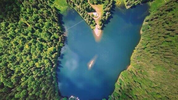 空中飞过美丽的山脉和森林绕着一个不可思议的蓝色湖泊的轴线旋转