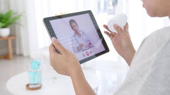 远程医疗概念近距离亚洲妇女视频电话与医生在客厅的家病人女孩咨询全科医生应用电脑平板医生及顾问在线