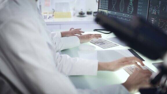 女科学家在电脑键盘上打字以DNA研究为背景的监视器