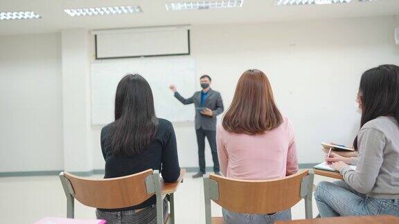 在大学的教室里老师站在教室的前面教学生学生戴口罩预防病毒感染