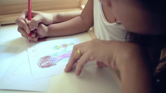 蹒跚学步的小男孩和他的妈妈在桌子上画画