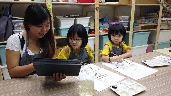 一位亚洲华裔女艺术教师在她的艺术课上教2名中国女青年学生水彩画和着色