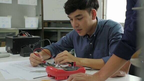 亚洲学生在教室里和老师一起学习电子学测量电路中的信号