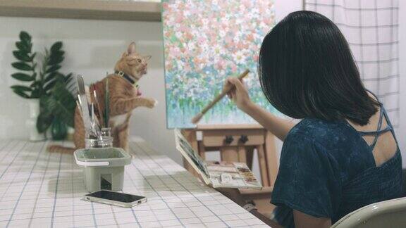 怀孕的艺术家在家里的工作室与虎斑猫一起工作