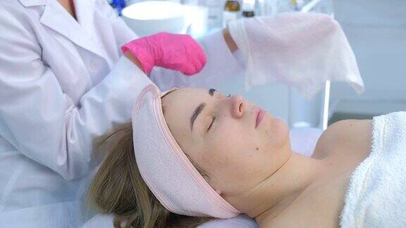 美容师正用热毛巾擦拭妇女脸上的保湿面膜