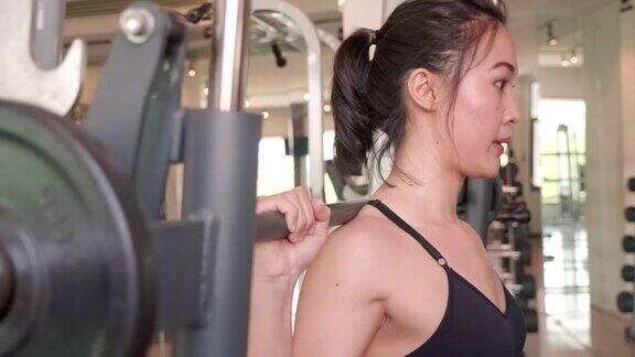 迷人的亚洲女孩在运动服装举起杠铃在健身体育馆里和反射镜人们的生活方式和体育理念4k录像视频