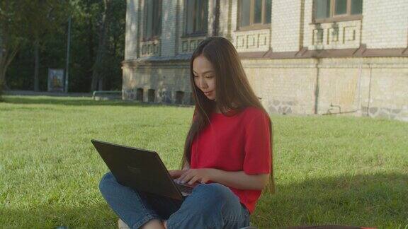 可爱的亚洲女学生在户外笔记本电脑上打字