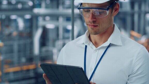戴着护目镜和安全帽的男工程师在汽车装配厂用平板电脑向外看在技术工厂从事汽车生产的工业专家