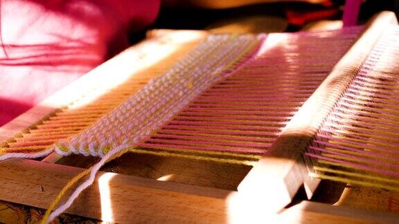 小女孩用织布机在家里自制的木架上织毛线