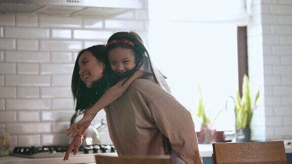可爱的亚洲母女在厨房里玩耍和拥抱