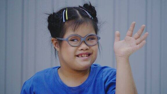 一个10岁的亚洲小女孩戴着眼镜带着唐氏综合症的微笑站在教室里看着摄像机残疾的肖像