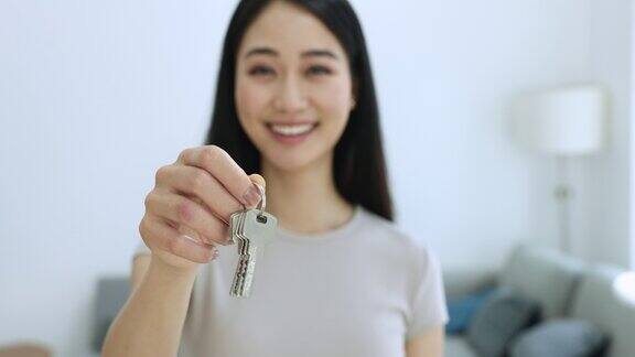 一位面带微笑的年轻女性房地产经纪人正在出售公寓的钥匙