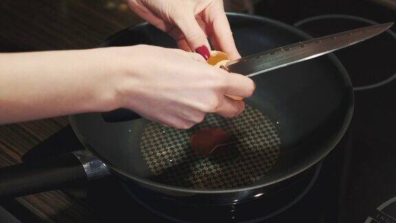 用刀打碎鸡蛋然后在平底锅上煎