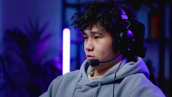 亚洲专业游戏玩家戴着耳机晚上在液晶显示器上玩在线虚拟视频游戏