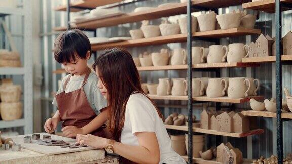 美丽的陶工在教她的儿子制作环保陶器