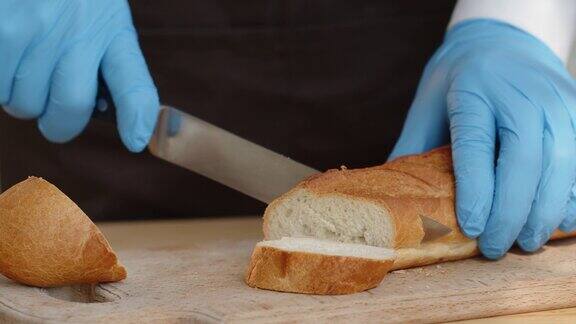 女人用刀切新鲜的面包长面包用来做三明治