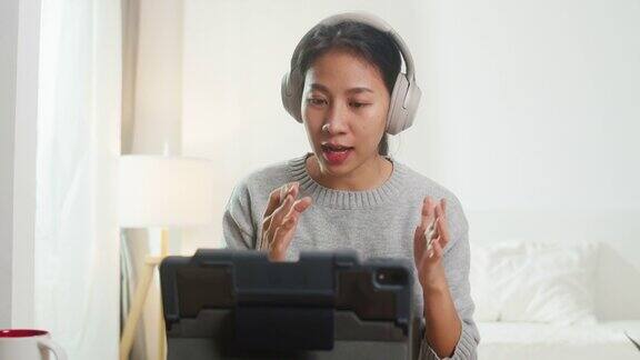 亚洲女商人戴着耳机用平板电脑与同事视频通话同时在卧室智能工作