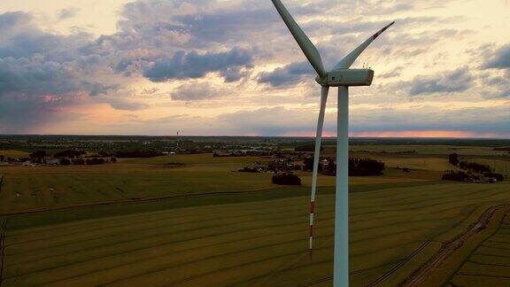 在晚霞和雨云中麦田中央的风力发电机产生可再生能源