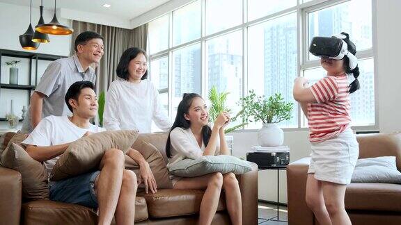 幸福亚洲家庭多年龄享受观看欢呼她的女儿一起玩vr眼镜的乐趣并退出在客厅的家庭内部背景