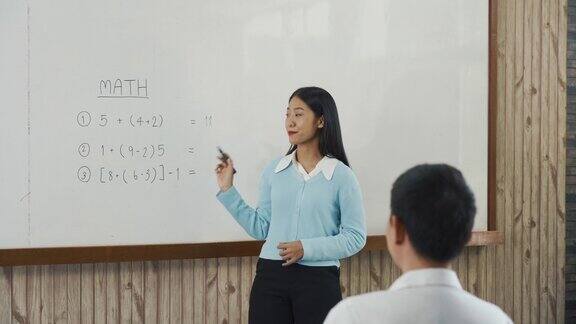 年轻的亚洲教师在教室里教学生