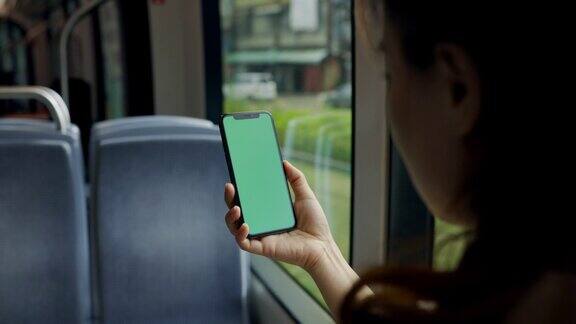 亚洲妇女在火车上使用绿屏智能手机