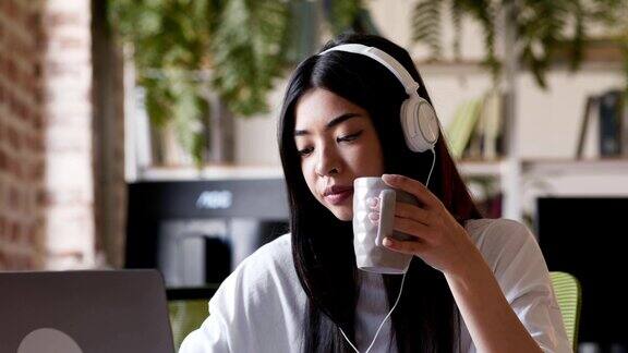 亚洲女孩在笔记本电脑上看网络研讨会和享受咖啡