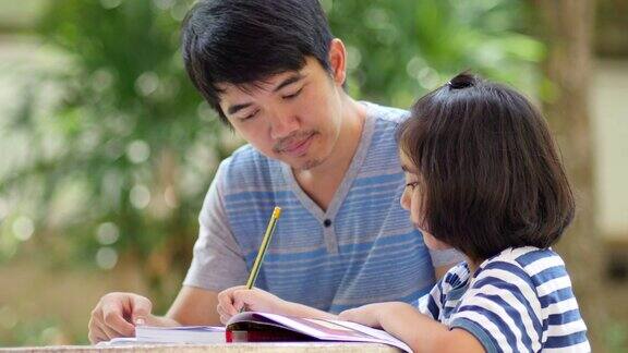 亚洲小女孩和爸爸在桌子上做作业