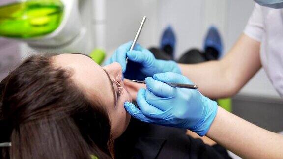 年轻的女牙医正在检查病人的牙齿近距离观察女牙医的手在手套拿着仪器牙齿健康和牙齿保健