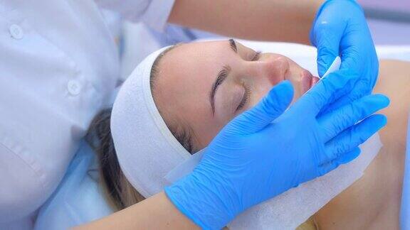 美容师医生用抗菌餐巾纸擦拭女性脸部双手特写